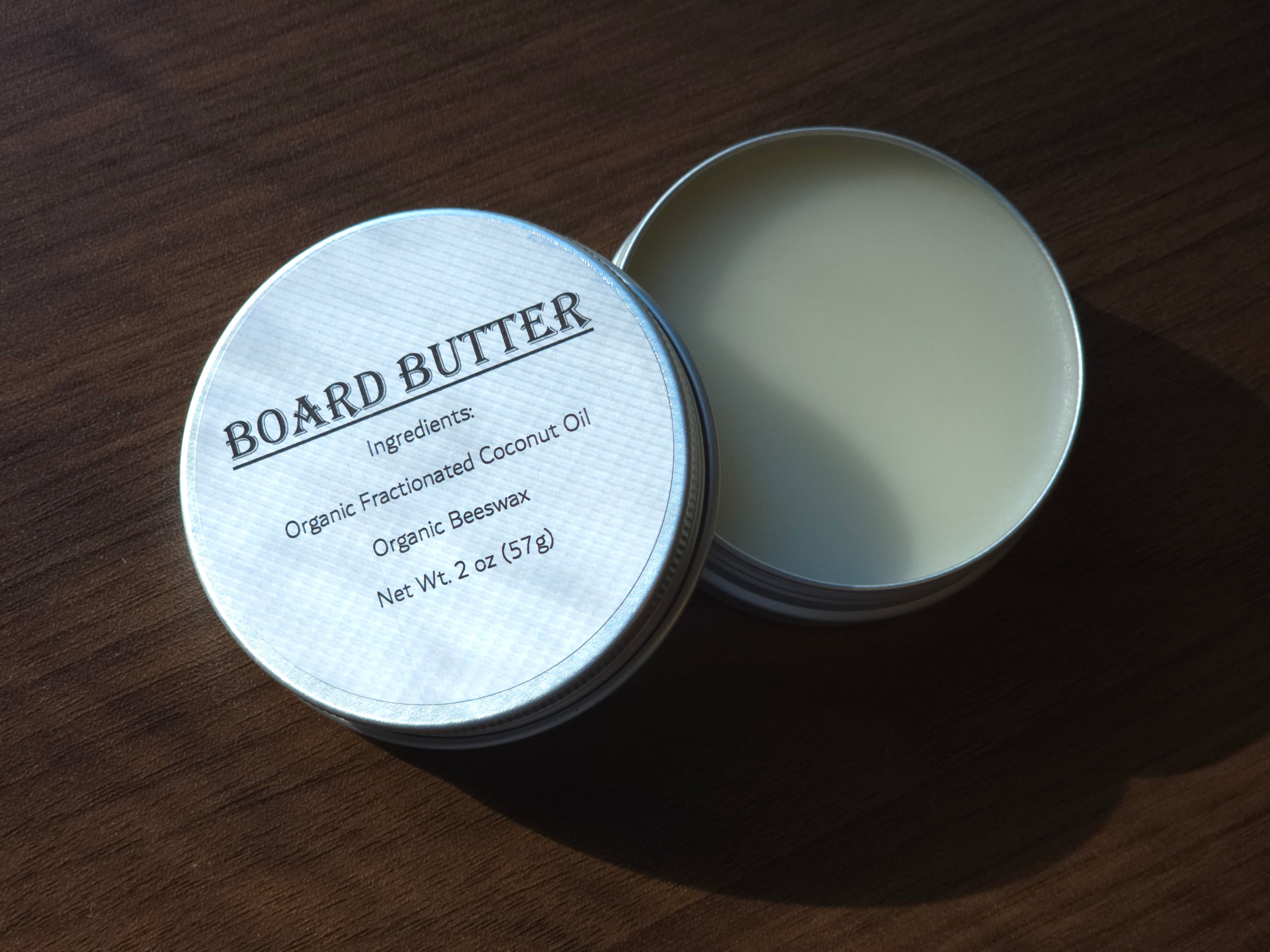 Open tin of ReDieming Creations Board Butter cutting board conditioner with label on a wooden surface