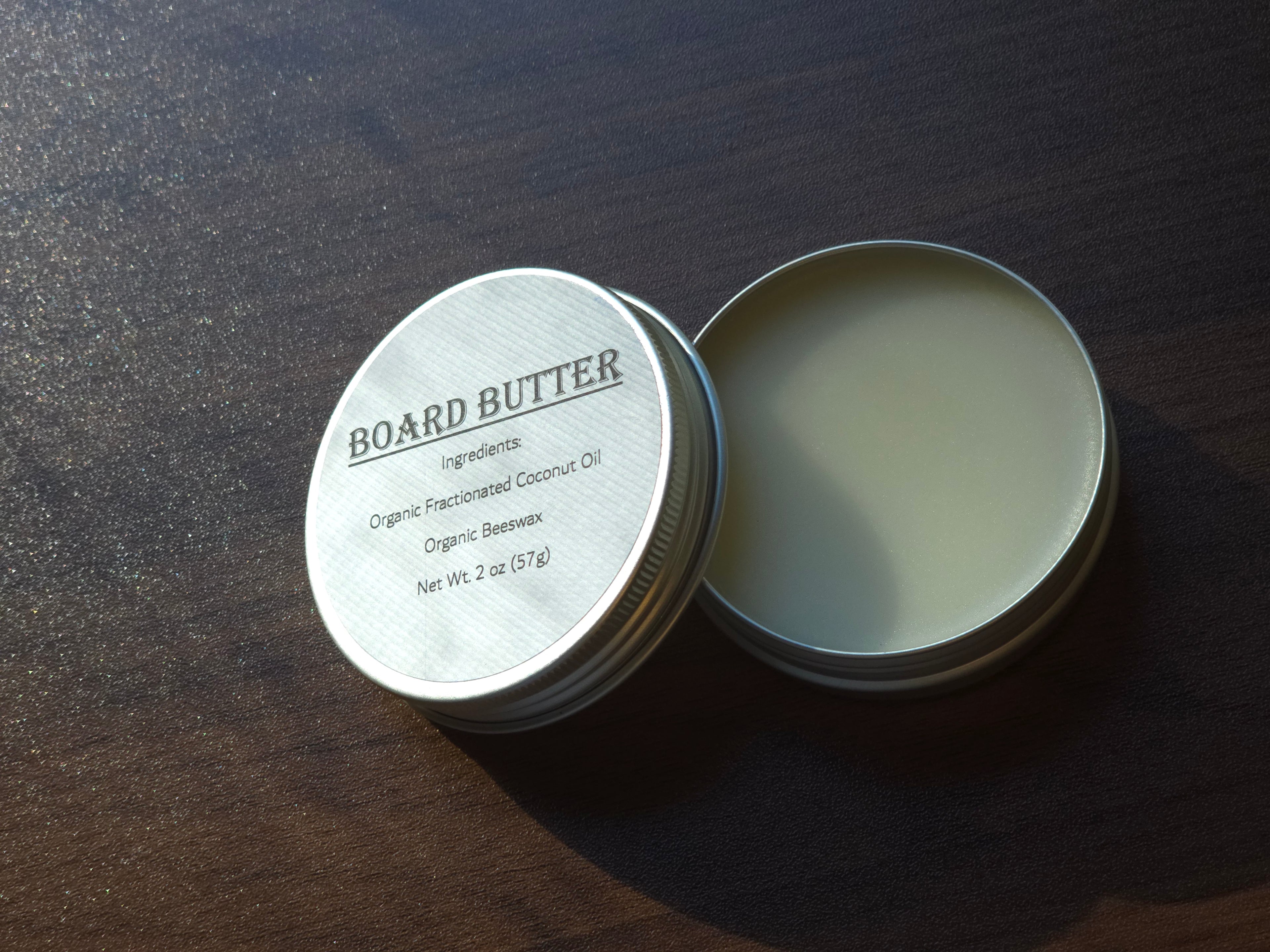 Open tin of ReDieming Creations Board Butter cutting board conditioner with label on a wooden surface